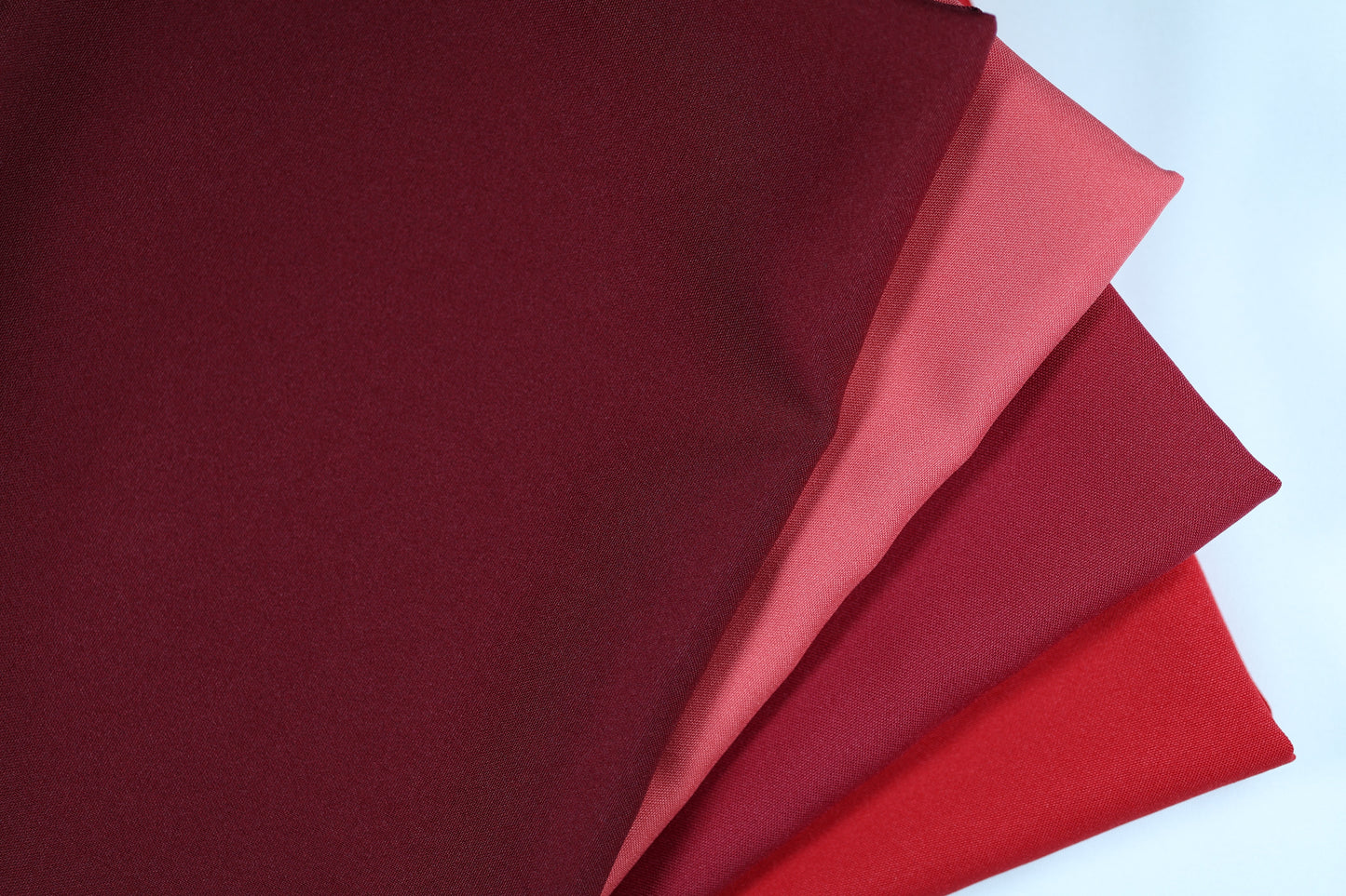 Polyester Panama Stoffe in Bordeaux- und Rot-Tönen – nebeneinandergelegt von Bordeaux über Rot bis hin zu strukturiertem Rot für elegante Farbvergleiche bei Dekostoffen