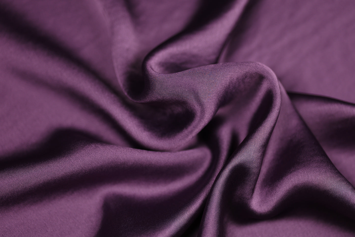 Nahaufnahme eines luxuriösen Satinstoffs in tiefem Aubergine mit edlem Glanz und weicher Faltenstruktur – perfekt für elegante Mode und kreative Projekte