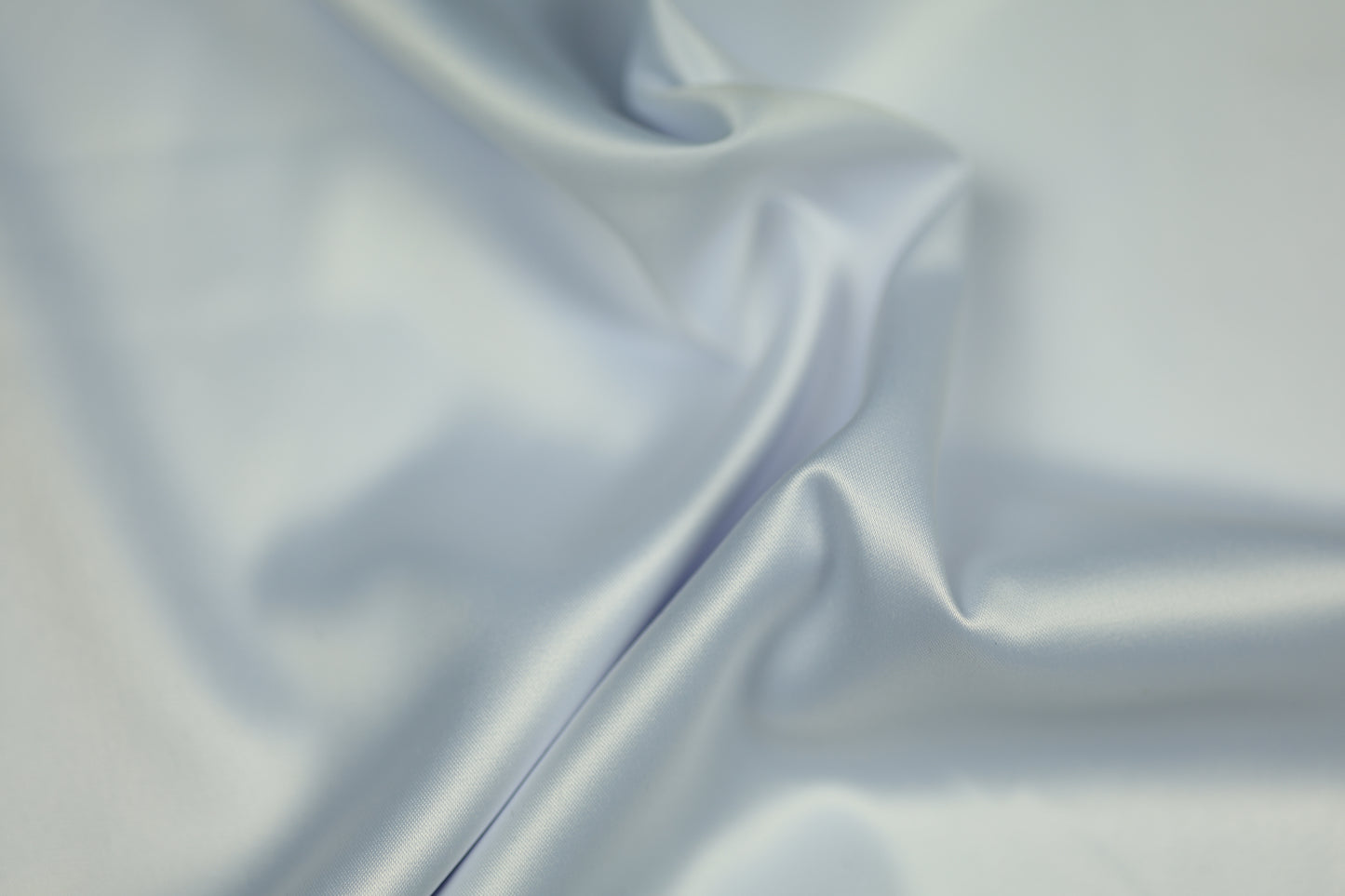Satinstoff in zartem Eisblau mit seidig glänzender Oberfläche und fließender Drapierung – perfekt für festliche Kleidung und elegante Dekorationen