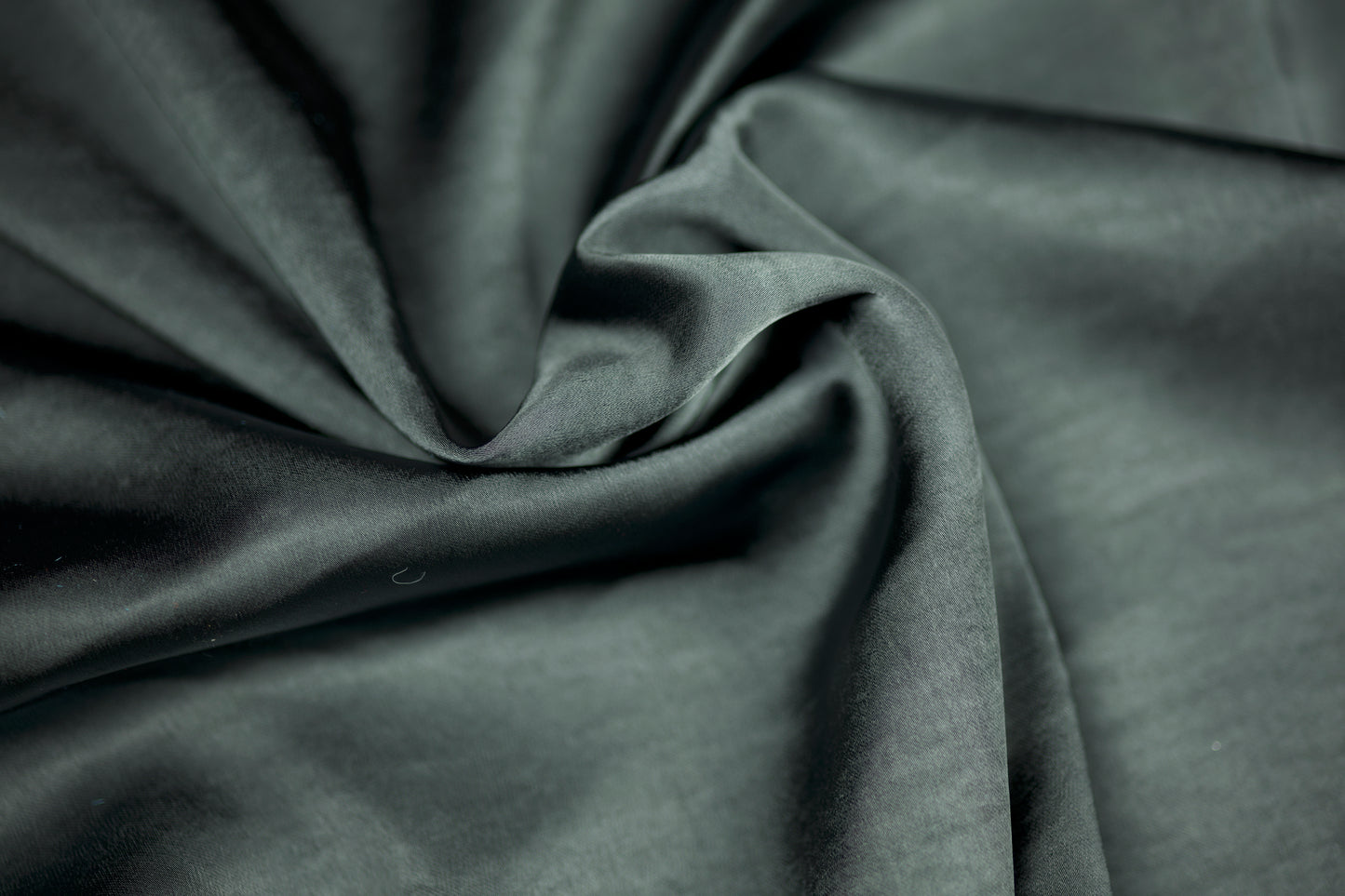 Nahaufnahme eines luxuriösen Satinstoffs in dunklem Schiefergrau mit elegantem Glanz und natürlichem Faltenwurf – ideal für stilvolle Nähprojekte