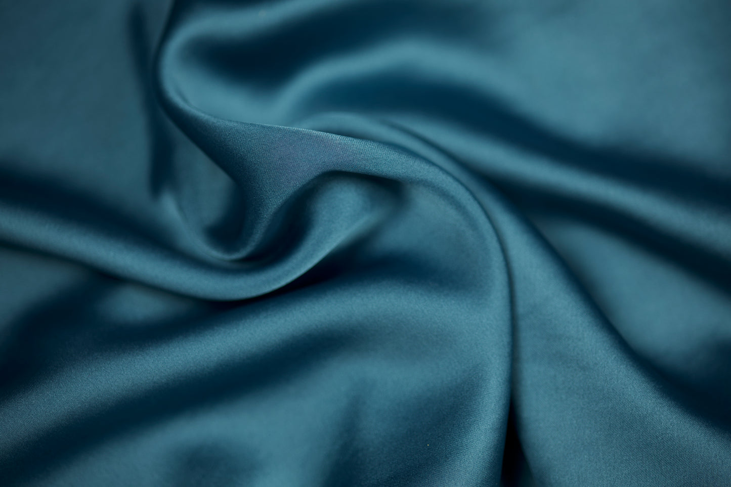 Nahaufnahme eines luxuriösen Satinstoffs in kühlem Stahlblau mit edlem Schimmer und geschmeidigem Faltenwurf – ideal für elegante Näh- und Dekoideen