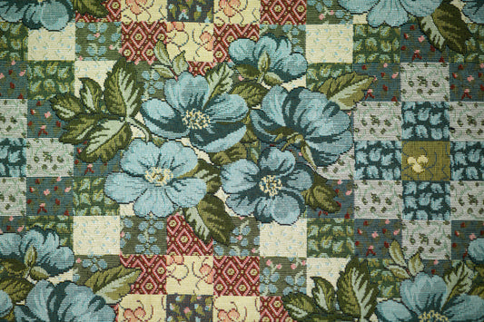 Bunter Möbelstoff mit Patchwork-Optik und blauen Blumen auf hellem Grund – perfekt für kreative Polsterprojekte